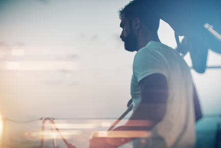 Portrait of young bearded man standing on a yacht and looking at the horizon
