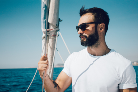 Portrait of young bearded man standing on a yacht and looking at the horizonの写真素材