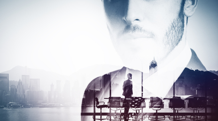 Bw close-up portrait of young businessman and meeting room on the background. Double exposure of office, city and gulf on the background.の写真素材