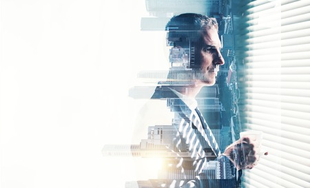 Close-up portrait of businessman wearing suit. Double exposure of panoramic city view at sunrise on the backgroundの写真素材