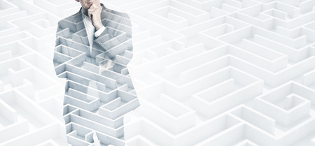 Young businessman wearing a suit thinking. Double exposure of the labyrinth on the background.の写真素材