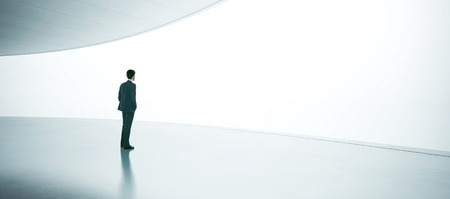 Young businessman wearing suit and stands in the open space interior. Wideの写真素材