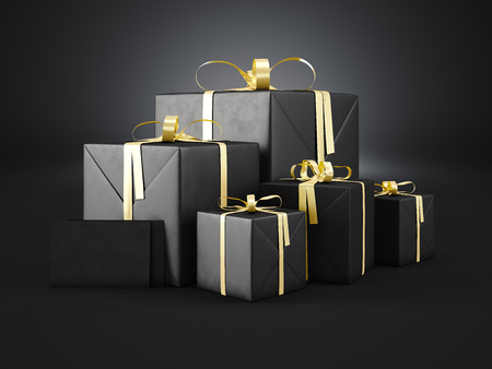 Set of black gift boxes of various sizes with golden ribbon bow and two blank envelope  on dark background.