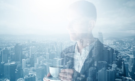 Photo of stylish adult businessman wearing trendy suit and holding cup coffee. Double exposure, panoramic view contemporary city.の写真素材