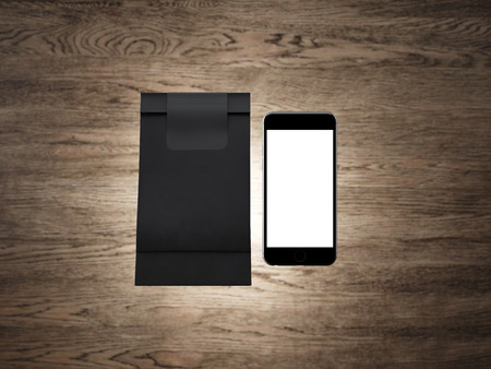 Set of blank coffee pocket and generic design smartphone. Wood background.の写真素材