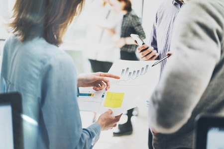 Account managers discussion. Photo documents holding hands. Picture businessmans crew working with new startup project. Idea, analyze marketing plans. Blurred background,light effectsの写真素材
