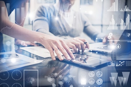 Closeup photo female hands touching screen modern tablet. Bankers team working new investment project in office.Using electronic devices. Graphics icons, stock exchanges interface.の写真素材