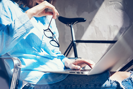 Work process modern Studio Loft.Creative manager working coworkers office with new freelance business startup.Using Laptop on knees,holding glasses hand.Horizontal.Film effect.Blurred backgroundの写真素材