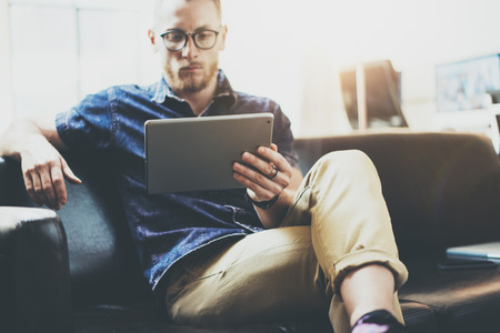 Stylish Businessman working tablet PC modern Interior Design Loft Office.Man relax Vintage sofa use contemporary device Hand.Blurred Background.Creative Business Startup Idea.Horizontal,Film effectの写真素材