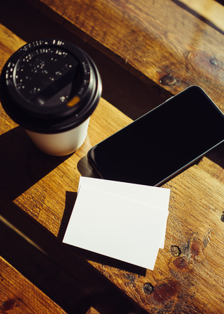 Blank White Business Card Mockup.Mobile Phone High Textured Wood Table Take Away Coffee Cup Cafe.Ready Work Modern Office Blurred Background.Clean Object Private Corporate Information Vertical.Mock Upの写真素材