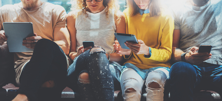 Four Hipsters Friends Sitting Sofa Using Electronic Gadgets.Creative Department Working Together Digital Devices.Coworking Process Office Studio.Friendship Technology Concept.Blurred.Business Startupの写真素材