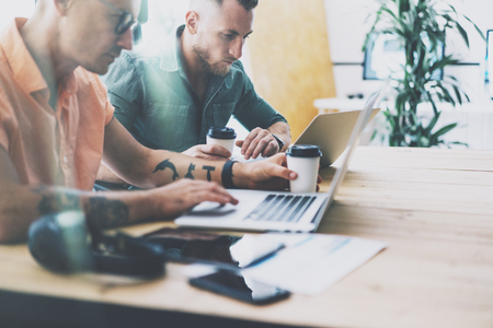 Two Tattoo Artist Working Wood Table Laptop Modern Interior Design Loft.Coworkers Work Office Studio.Hipsters Contemporary Notebook Digital Tablet New Art Project.Blurred Background. Business Startupの写真素材