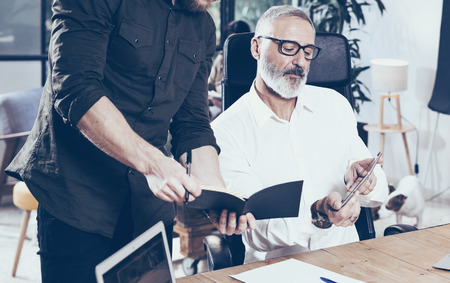 Closeup view of adult businessman and his assistant making great brainstorming in modern office.Bearded man talking with colleague about startup project.Business people discussion concept.Horizontal.の写真素材