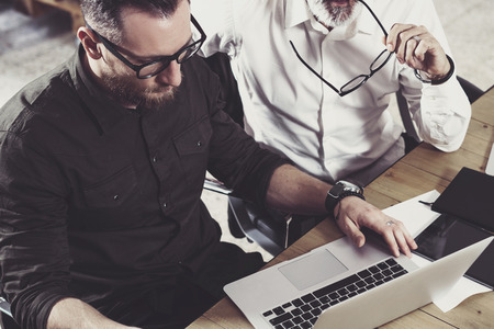 Closeup view of bearded man working together with adult businessman colleague at the wooden table.Business people teamwork concept.Horizontal,blurredの写真素材