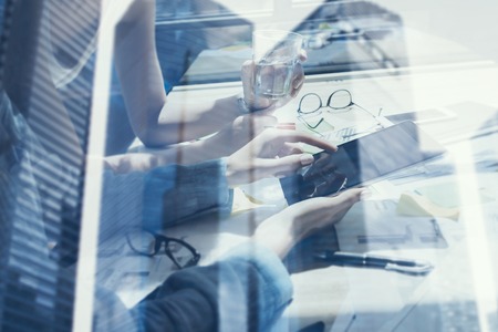 Concept of coworking people using mobile gadgets.Closeup view female hands touching display digital tablet.Double exposure,modern skyscraper office building on blurred background.Horizontalの写真素材