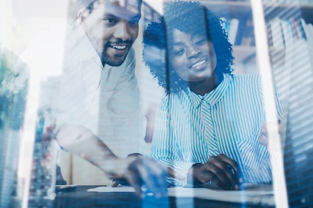 Concept of double exposure.Two young coworkers working together in a modern office.Black business partners discussing new startup project.Skyscraper office building blurred on background.Horizontalの写真素材