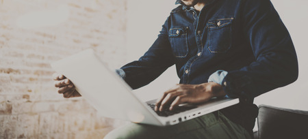 Bearded young African man using laptop while sitting at his modern coworking place.Concept of happy...