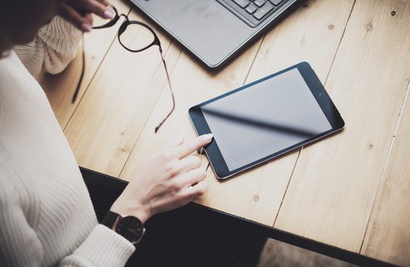 Top view of female hand touching digital tablet on the wooden table.Concept young business people using mobile devices.Horizontal, blurred background.の写真素材