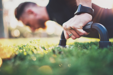 Crossfit lifestyle concept.Closeup view of male hand while doing pushups in the park on the sunny morning.Training outdoors.Fit shirtless male fitness healthy model in exercise outdoors.Blurred.の写真素材