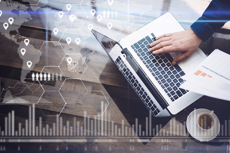 Concept of digital screen,geolocation icon,virtual diagram,graph interfaces.Man working with laptop at office at wooden table.Reflections on glass surface.Horizontal.の写真素材