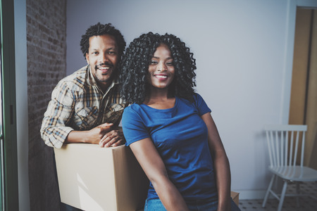 Young black african man and his girlfriend moving boxes into new house together and making a...