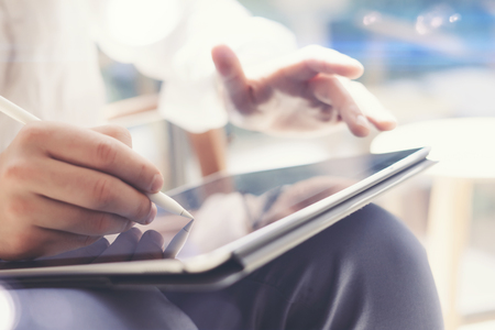 Closeup view of man holding tablet on hand and using electronic pen while working at office.Pointing...