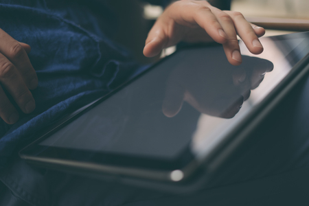 Close-up view of male hands touching digital tablet screen. Blurred background. Horizontal.の写真素材