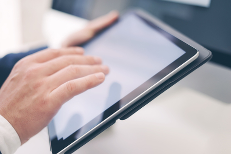 Closeup view of two male hands holding electronic tablet and touching screen.Businessman working at...