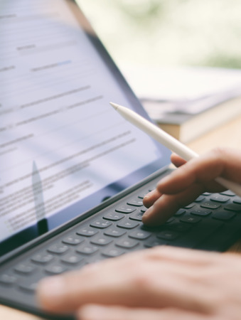 Blogger using mobile touchpad for work.Closeup view of male hands typing electronic tablet keyboard-dock station.Vertical,blurred background.の写真素材