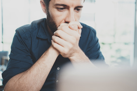 Closeup view of Hispanic young businessman thinking new business idea while working at sunny office.Blurred background. Horizontalの写真素材