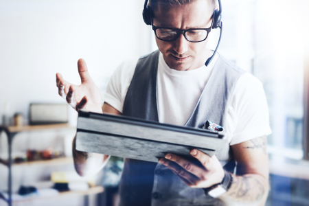 Businessman wearing audio headset and making video conversation via digital tablet.Elegant man working on his digital tablet holding in hands. Blurred background.Cropped.の写真素材