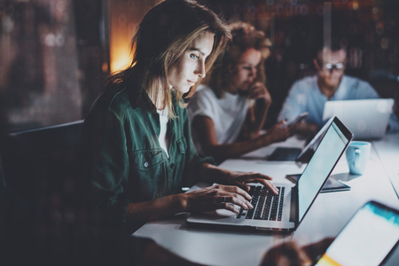 Team of young coworkers working together at night office.Young woman using mobile laptop at the...