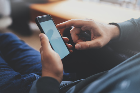Male finger pointing to touch screen of modern smartphone . Blurred background.Blogger using mobile gadget. Horizontalの写真素材