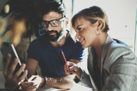 Coworkers working process at home.Young blonde woman working together with bearded colleague man at modern home office.People using electronic devices.Blurred background.Horizontal.の写真素材