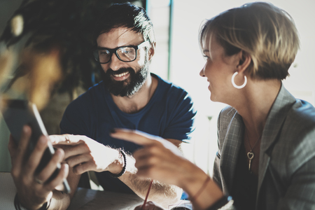 Coworkers working process at home.Young blonde woman working together with bearded colleague man at modern home office.People using electronic devices.Blurred background.Horizontal.の写真素材