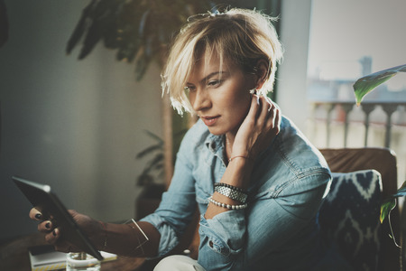 Smiling young woman wearing casual clothes and using electronic device while spending relax time...
