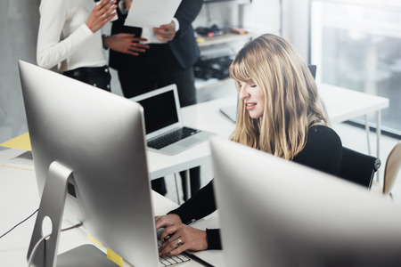Group of businessmans working on desktop computer in lightful office.Woman typing on computer keyboard. Horizontal, blurred background.の写真素材