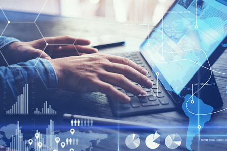 Concept of virtual diagram,graph interfaces,digital display,connections,statistics icons.Man using contemporary electronic tablet with dock keyboard.Blurred background. Horizontal.の写真素材