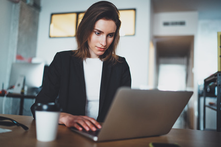 Portrait of handsome businesswoman using laptop computer at modern office.Blurred background.Horizontal.の写真素材