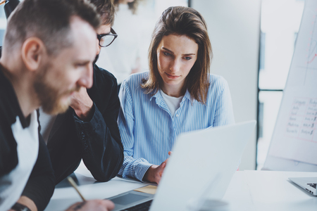 Three coworkers at working process.Young woman working together with colleague at modern office.Teamwork concept. Blurred background.Horizontal.の写真素材