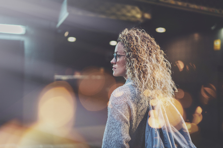 Pretty young woman hipster in stylish clothing wearing eye glasses traveling in the european night city. Bokeh and flares effect on blurred background.の写真素材