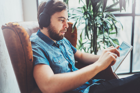 Young hipster wear casual clothes listening music in headphones on touch tablet at modern home place.Horizontal.Blurred background.の写真素材