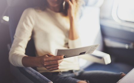 Enjoying business travel concept. Young beautiful brunette tourist girl travelling on the train sitting near the window using smartphone,holding ticket hands.の写真素材
