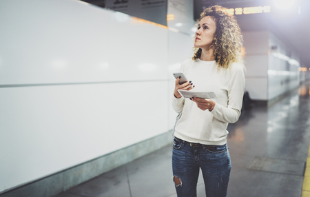 Attractive woman on transit using smartphone while walking with hand luggage backpack in train station or airpot going to boarding gate.Enjoy railroad transport concept.の写真素材