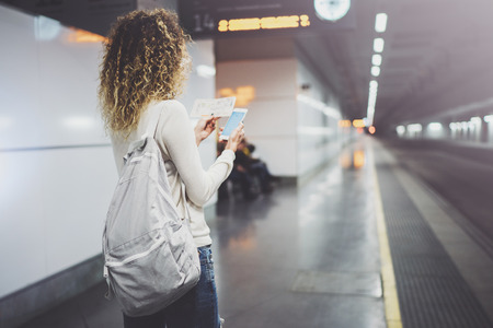 Beautiful girl happy using mobile phone app for conversation in holiday travel.Attractive woman on transit platform using smartphone while waiting rail train on station.の写真素材