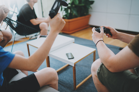 Group of happy friends sitting on a sofa in living room and playing video games. Family relaxing time at home concept.の写真素材
