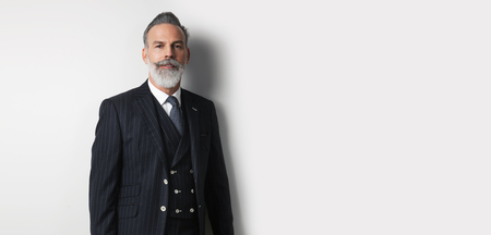 Portrait of bearded handsome businessman wearing trendy suit over empty white background. Copy Paste text space. Wide.の写真素材