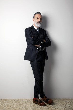 Portrait of confident bearded middle aged gentleman wearing trendy suit standing over empty white background. Studio shot. Verticalの写真素材