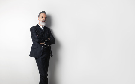 Portrait of bearded confident gentleman wearing trendy suit standing over empty white background. Copy Paste text space.の写真素材