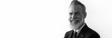 Portrait of bearded smiling gentleman wearing trendy suit over empty white background. Copy Paste text space. Wide. Black and Whiteの写真素材